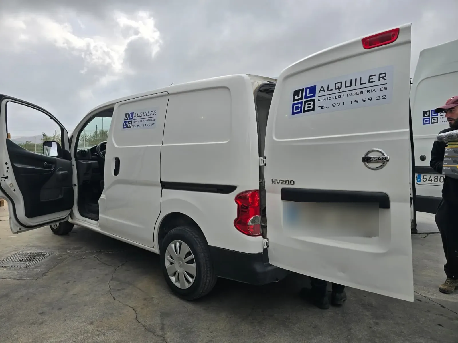 Nissan NV200 blanca de alquiler JLCB con las puertas traseras abiertas
